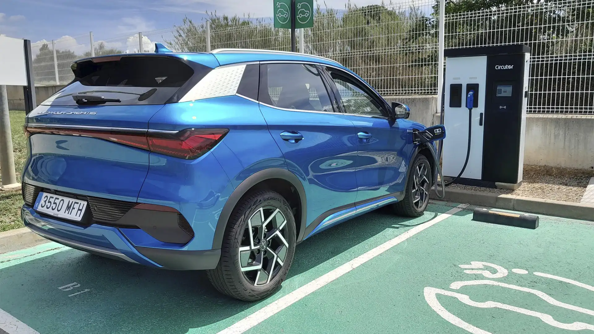 Vehículo eléctrico BYD Atto 3 en color azul estacionado junto a un cargador de coche de Circutor.