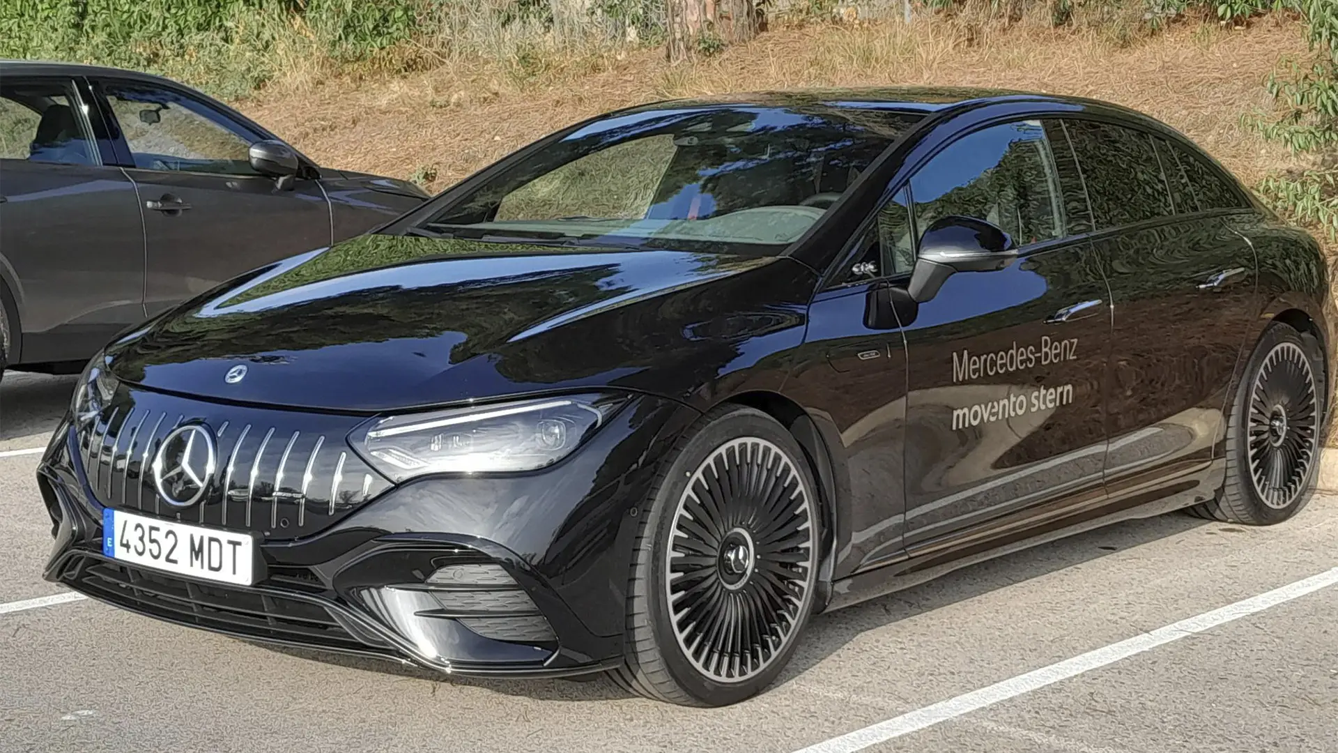 Vehículo eléctrico Mercedes EQE AMG de color blanco en un punto de recarga.