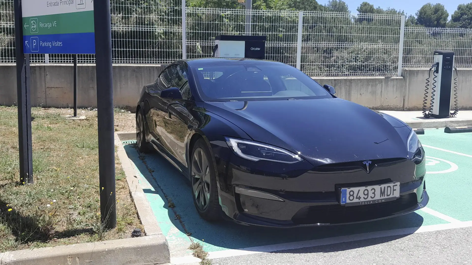 Vehículo eléctrico Tesla Model S de color gris cargando su batería en una estación.